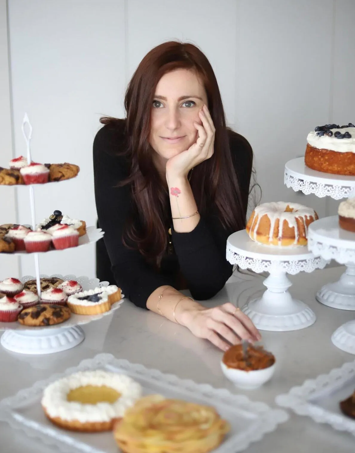 Aura Danton seated at a table of cakes, tarts, and pastries