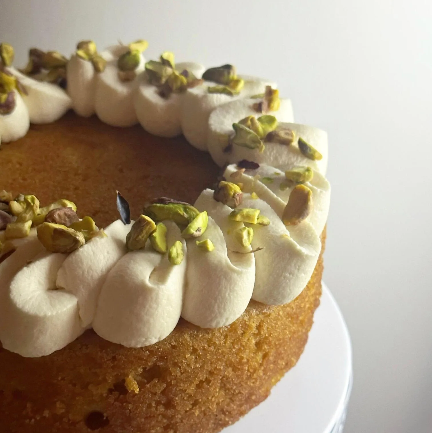 Cake piped with cream and finished with pistachios